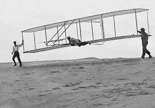 Two men launching the 1902 Wright glider from a dune.